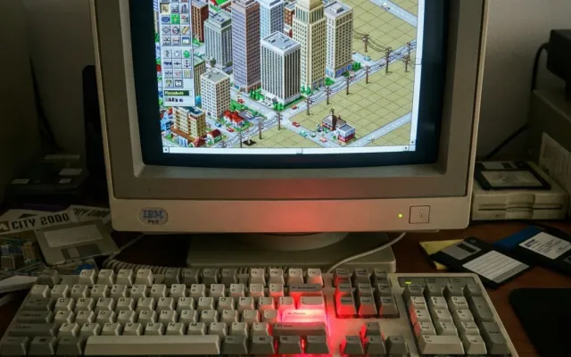 Monitor retrô exibindo o jogo de simulação urbana SimCity com vista isométrica de edifícios