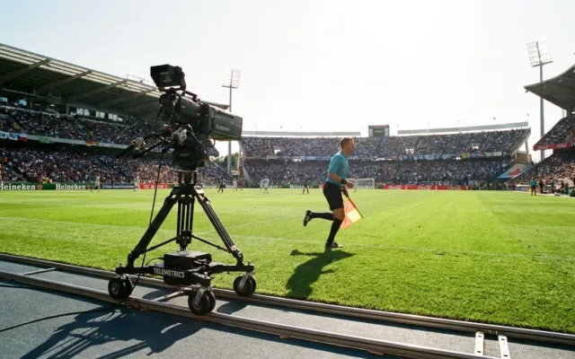 Câmera de transmissão automatizada gravando partida de futebol em estádio