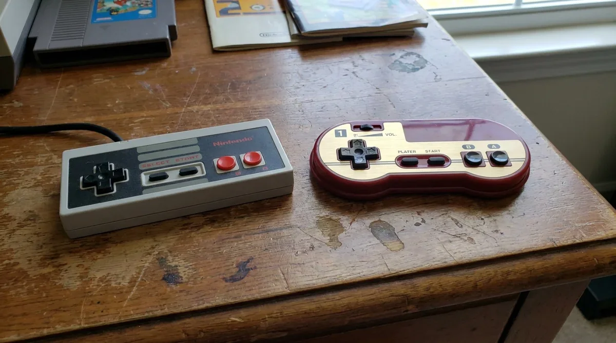 Comparação entre o controle cinza do NES ocidental e o controle vermelho e dourado do Famicom.